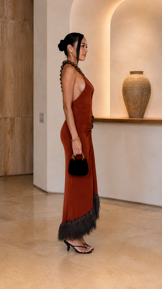 Side view of rust open-back halter maxi dress with feather-look hem