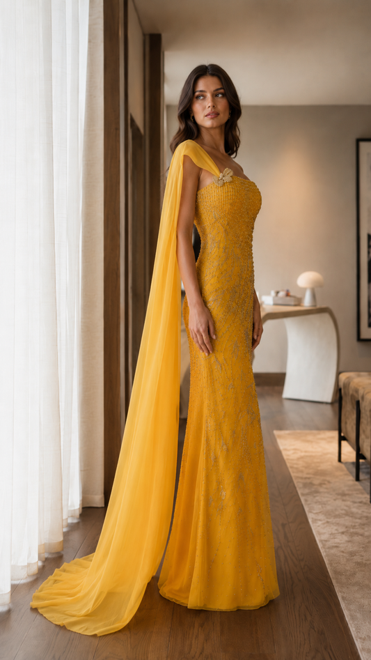 Side angle of marigold embellished one-shoulder formal gown with long cape