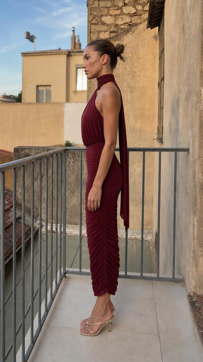 Side profile view of burgundy ruched dress with back tie detail