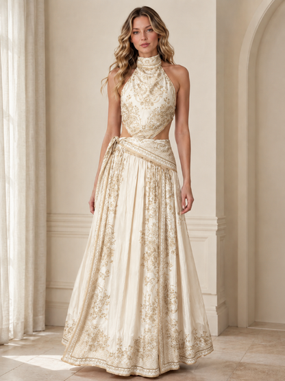 Front view of champagne halter maxi dress with ornate print and full flowing skirt