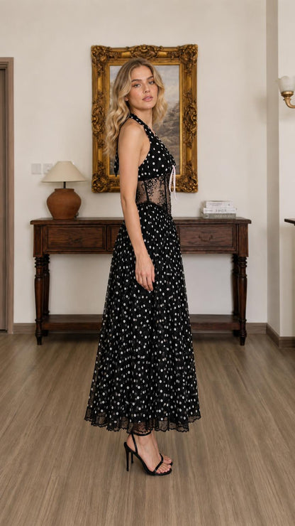 Side profile view of black polka dot halter midi dress