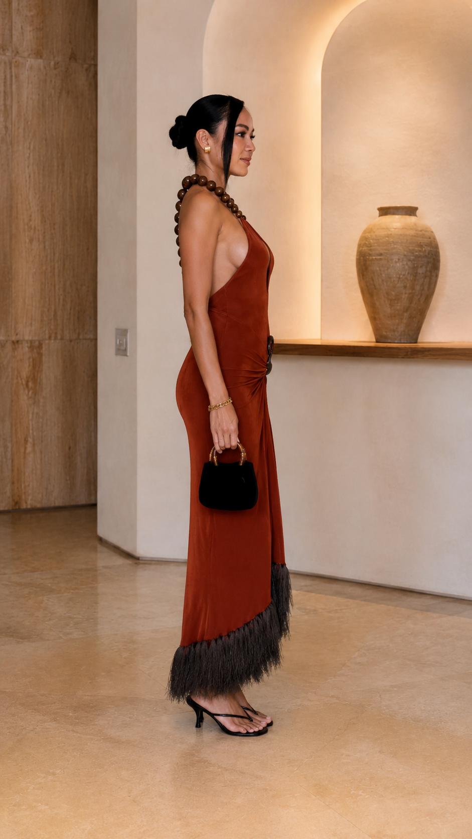 Side view of rust open-back halter maxi dress with feather-look hem