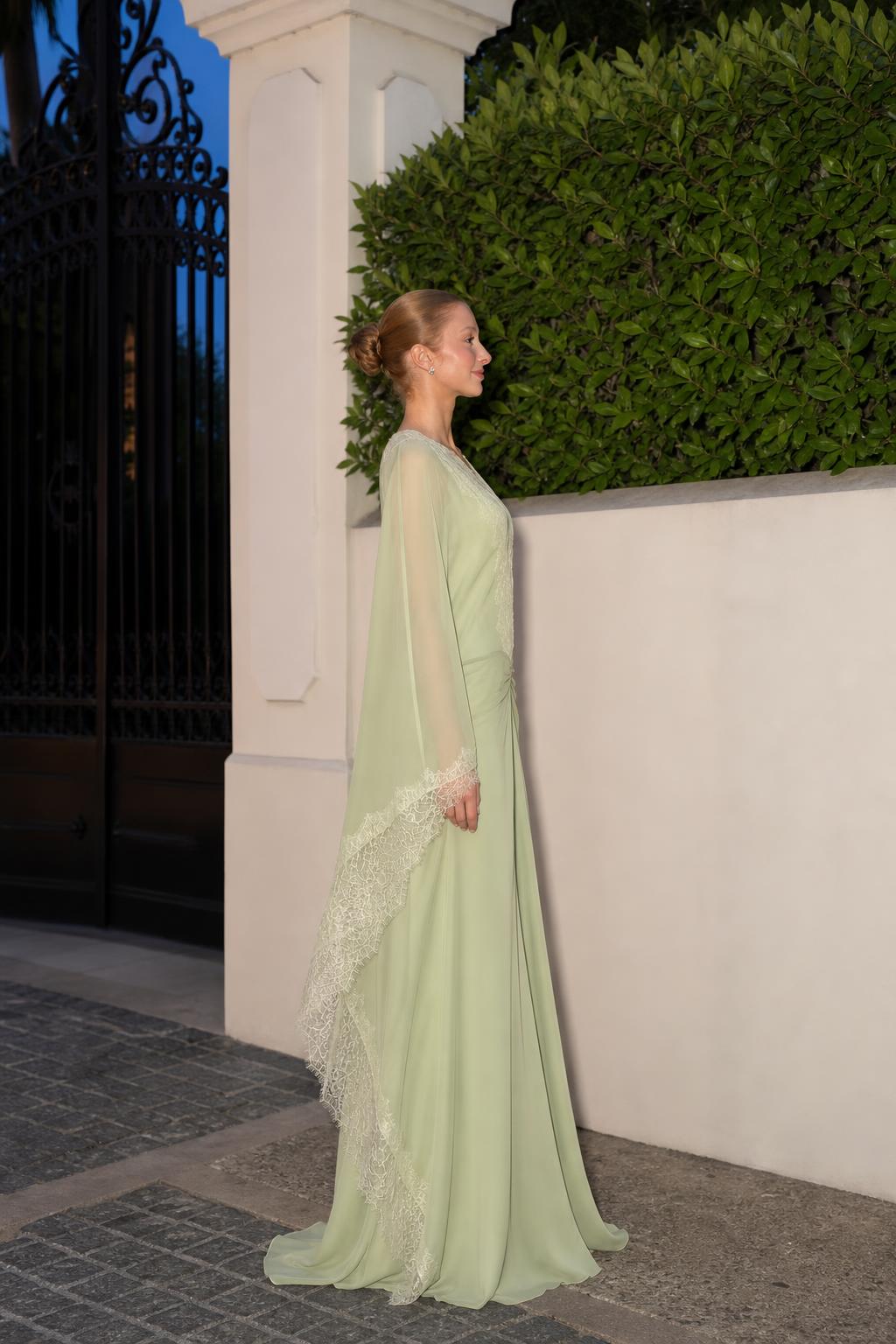 Model wearing sage green evening gown, side profile view