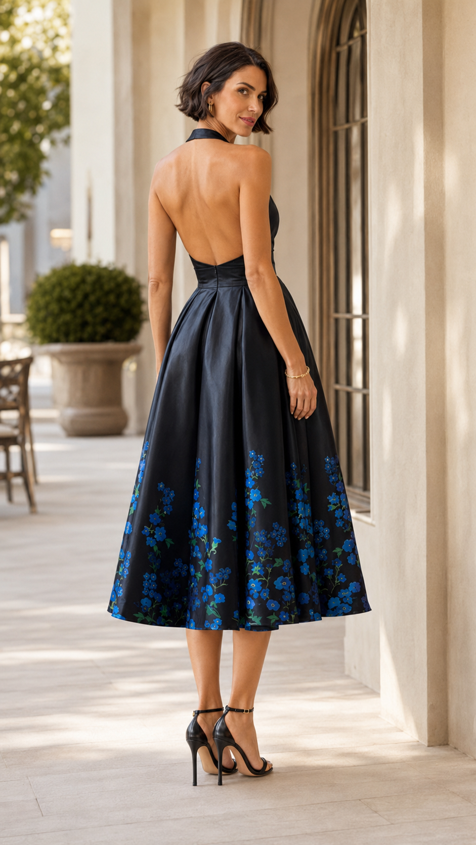 Back view of black open-back halter midi dress with blue floral hem print