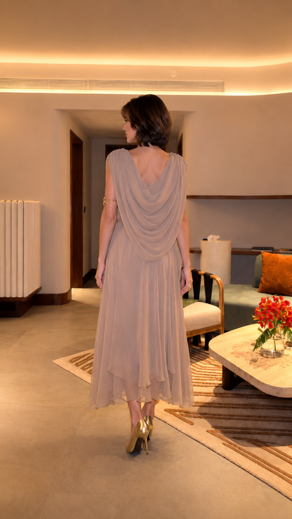 Back view of taupe draped midi dress showing flowing overlay and layered hem