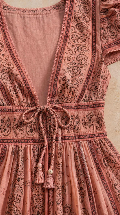 Close-up detail of V-neckline and tassel tie on pink dress