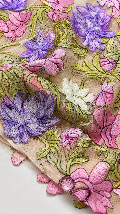 Close-up detail of multi-colored floral embroidery on sheer mesh