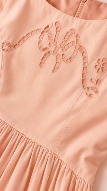 Close-up of cutwork bow embroidery on peach dress
