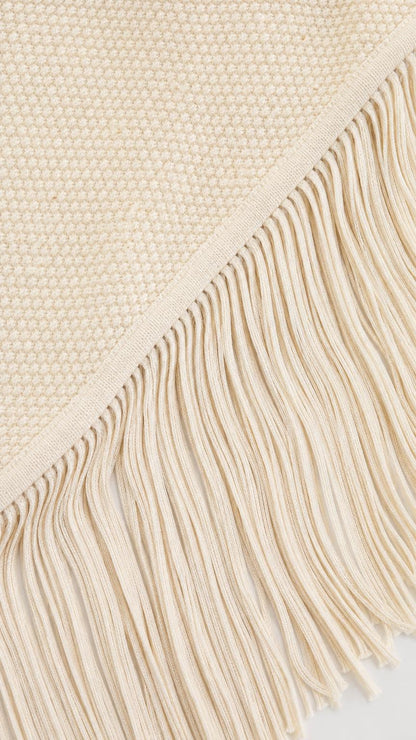 Close-up detail of the textured knit fabric and fringe hem