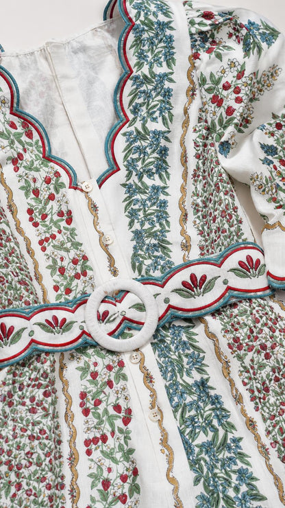 Close-up detail of embroidery, buttons, and belt on white romper