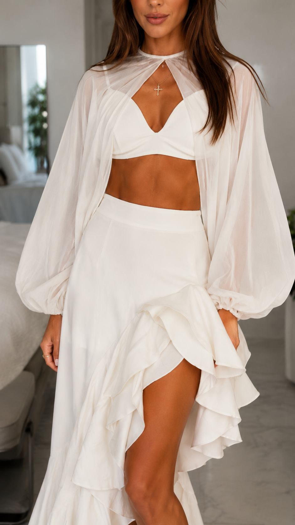 Close-up of white halter-style cutout dress with sheer draped sleeves and ruffle skirt