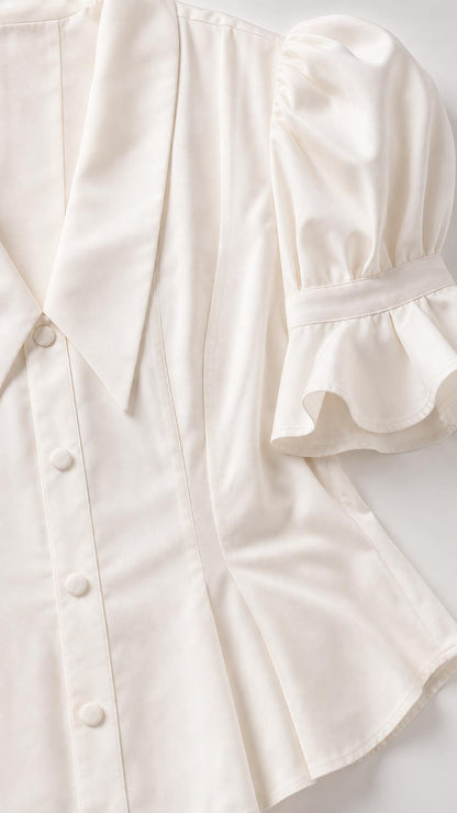 Close-up detail of white top collar, buttons, and puff sleeve ruffles