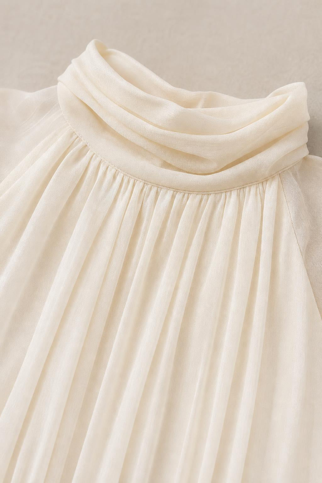 Close-up detail of high mock neckline and chiffon pleating