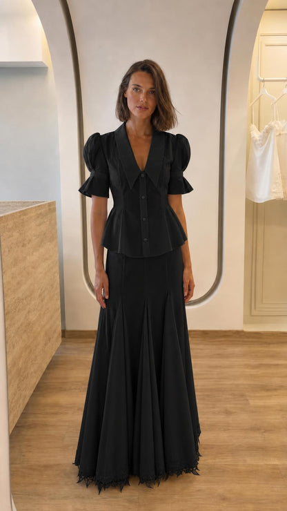 Front view of woman in black two-piece peplum top and maxi skirt set