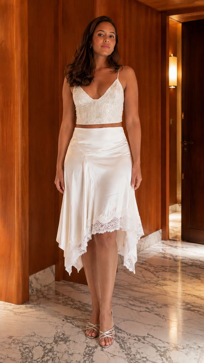 Front view of ivory lace-look crop top and ivory asymmetrical satin-look midi skirt set