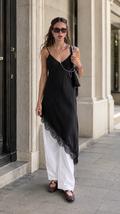Front view of black V-neck slip tunic with lace-trim angled hem over white pants
