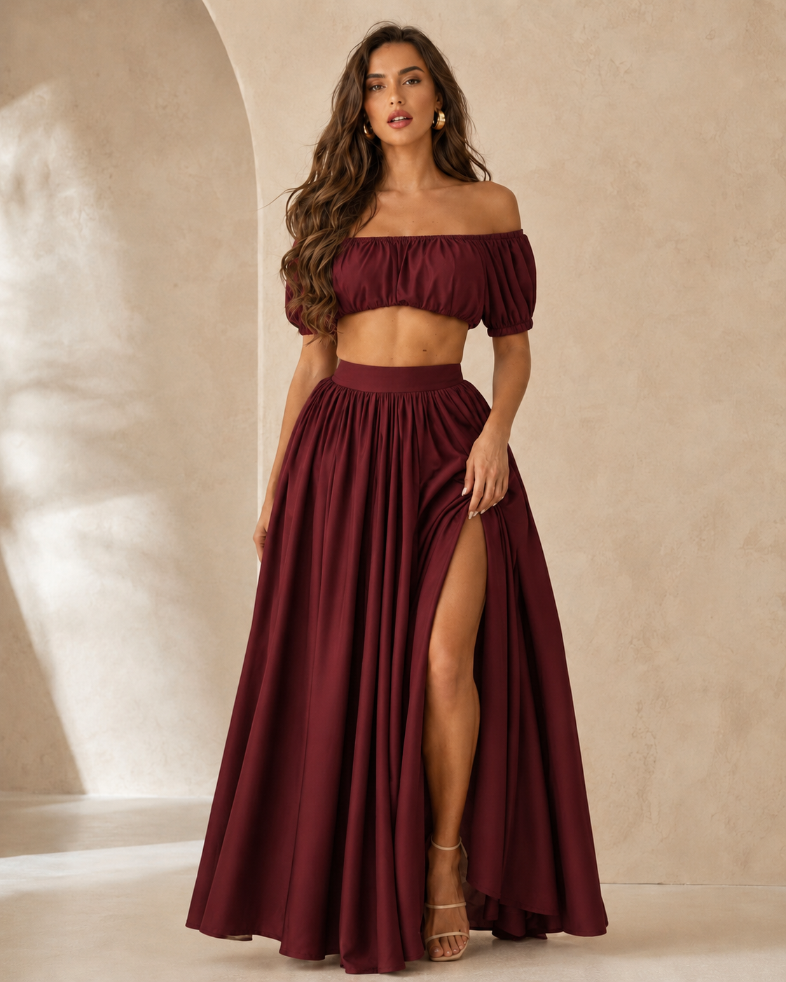 Woman wearing a burgundy off shoulder crop top and maxi skirt set with side slit front view