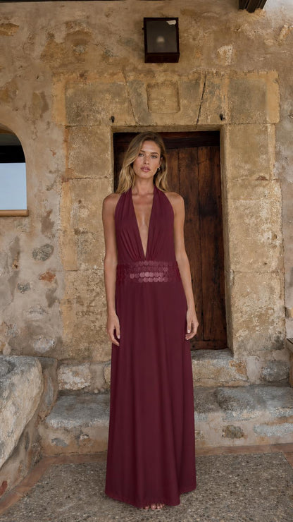 Front view of woman wearing burgundy halter neck maxi dress